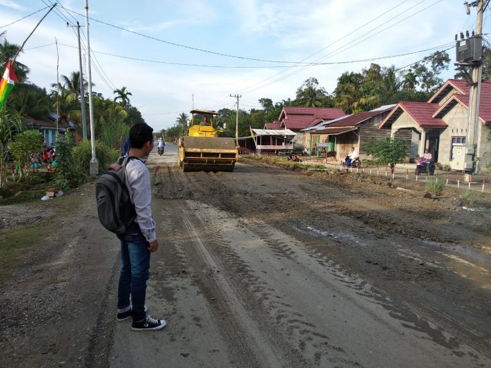 Aktivis Muda Rokan Hulu, Alfa Syahputra tengah melihat Dinas PUPR Rohul memperbaiki jalan rusak tersebut