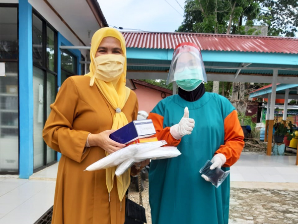 Anggota DPRD Rokan Hulu Fraksi Golkar, Hj Hasmeri Yulinawati menyerahkan APD kepada salah satu tenaga medis di Puskesmas Rambah