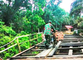 Jembatan Rusak Parah, Babinsa Bantu Sebrangkan Warga