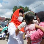 Ketua PMI Kabupaten Rohul Hj Peni herawati Sukiman sedang memasangkan masker keapda salah seorang balita saat pemberian masker kepada pengunjung pasar desa di Kecamatan Rambah Samo